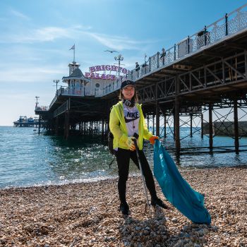 Lone female beside Brighton pier cleaning the beach