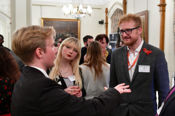 Three people dressed in smart office clothing standing engaged in a conversation