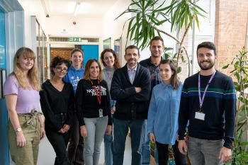Nine members of Professor Georgios Giamas' lab stand facing and smiling at the camera.