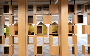 Wooden screen with movable boxes. Behind it there are quiet study areas in the shape of beach huts