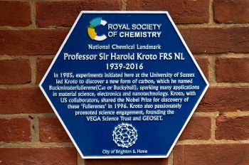 A close up of a hexagonal blue plaque against a red brick background. The plaque reads: Royal Society of Chemistry National Chemistry Landmark. Professor Sir Harold Kroto FRS NL 1939-2016.