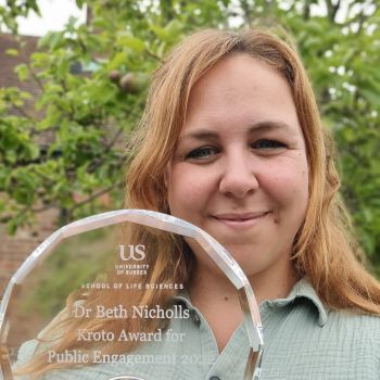 Beth Nicholls holding up the glass trophy for the Public Engagement Award