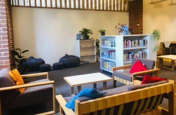 The Library Wellbeing Collection area with hundreds of print books and comfortable seating.