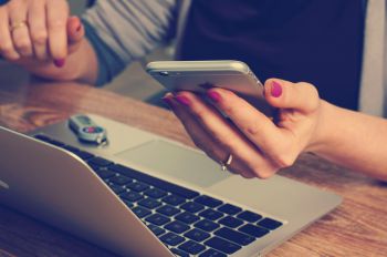 Student holding phone, next to laptop