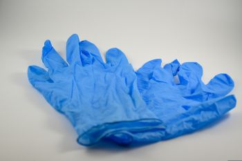 A pair of blue disposable gloves used for surgical procedures close up on a neutral background