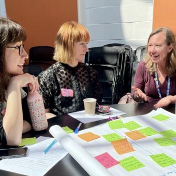 Three members of staff collaborating with post-its notes in a sunlit room