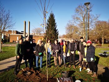 A Green Impact Team, dressed in outdoor wear and holding shovels, coming together for a tree planting activity on campus.