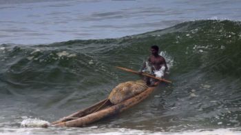 A fisherman on a kattumaram raft, made of logs tied together, deftly negotiating shore waves on a monsoon day.