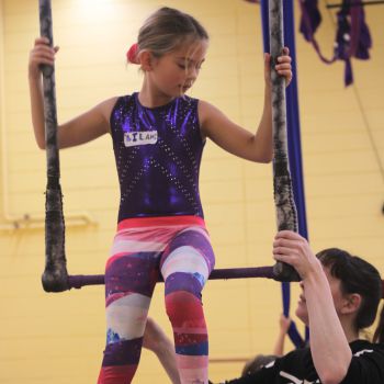 Girl on a trapeze being coached by instructor
