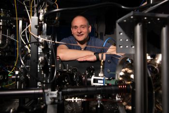 Professor Winfried Hensinger crossing his arms behind a prototype of a quantum computer in the quantum technologies lab at the University of Sussex