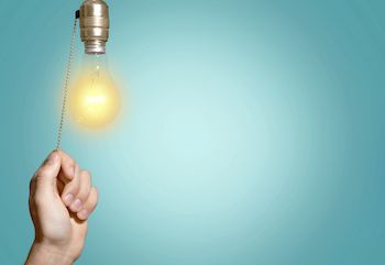 Hand pulling a toggle to turn off the lightbulb handing above it
