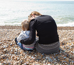A woman sat on the beach with a child