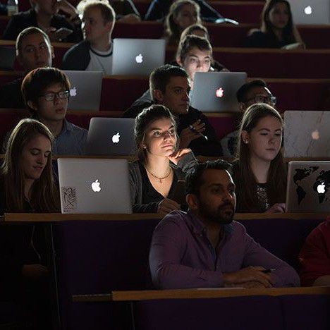 students sit with laptops in a lecure theatre