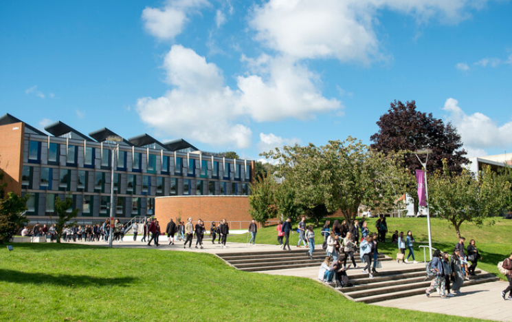 Students walking on steps outside Business School on sunny day