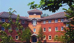 Lewes Court,  a red brick three story building framed by trees