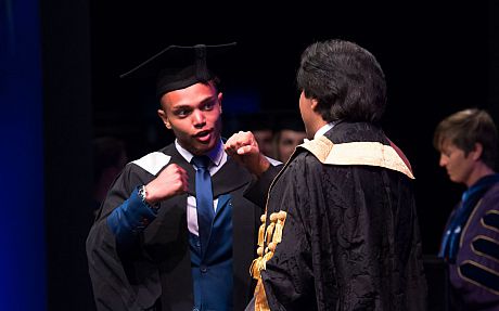 A graduand and Sanjeev celebrating on stage