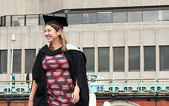 graduate standing in front of the Brighton Centre
