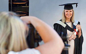 A student gets her picture taken professionally at her graduation ceremony