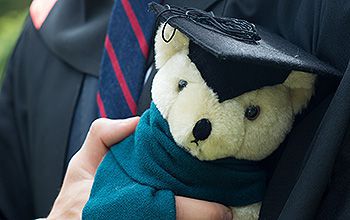 A graduate holding a teddy bear bought from the souvenir stall