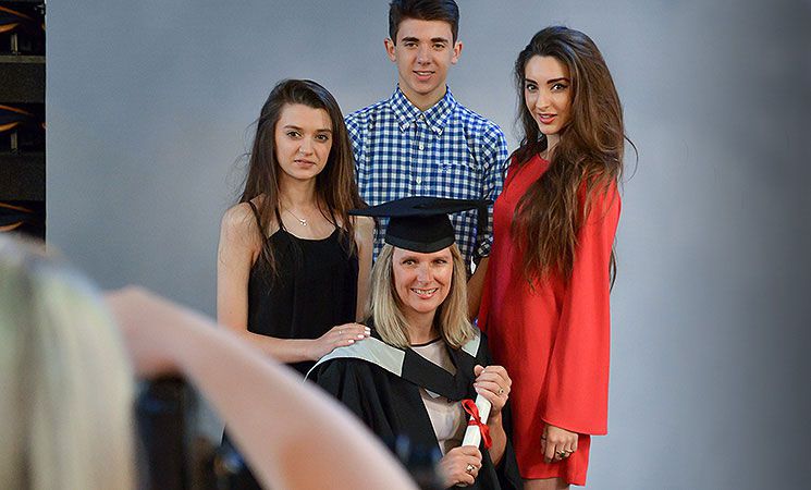 A graduand gets photographed with her family at a ceremony