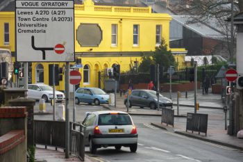 Road sign of vogue gyratory with car driving past