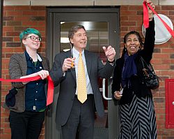 Michael Farthing cutting ribbon outside building.