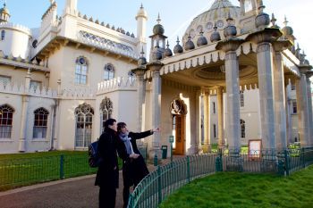 A photo of Alexandra Loske and Lu Peng standing outside the Royal Pavilion, looking into Pavilion Gardens