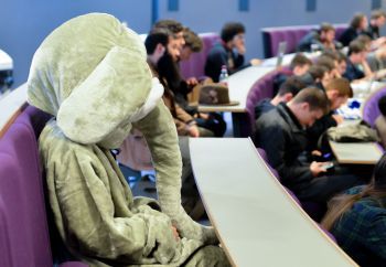 A photo of an actor dressed as an elephant, sitting in a lecture