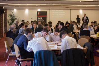 A photo of students sitting round a table in Bramber House, working on analysing a business case study