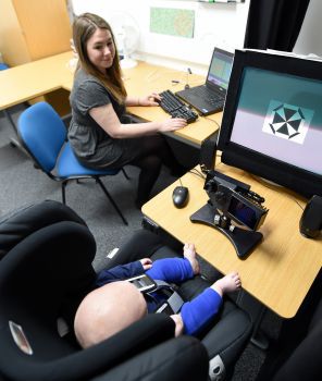 Baby Lab research assistant Alice Skelton (above) uses an eye-tracking device to observe how baby Georgios responds to visual stimuli.