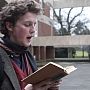 A student in Falmer House courtyard reading from a library book