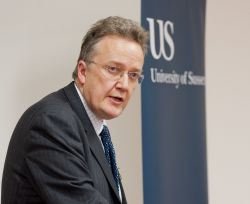 A man speaking with a University of Sussex sign in the background