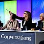 A panel of speakers, with one pointing to an audience member