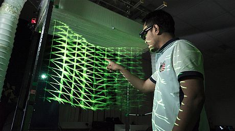 Person interacting with a futuristic interface that is green and emitting light.