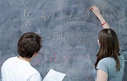 Undergraduate maths students writing on blackboard