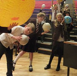 Primary school students holding inflatable planets