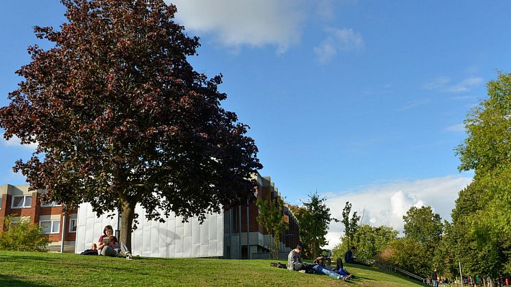 Adarsh Ramdawor seated at a picnic table in front of a campus building