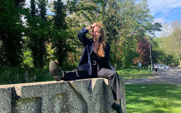 Sarah Osborn sat on the concrete University of Sussex sign on campus.