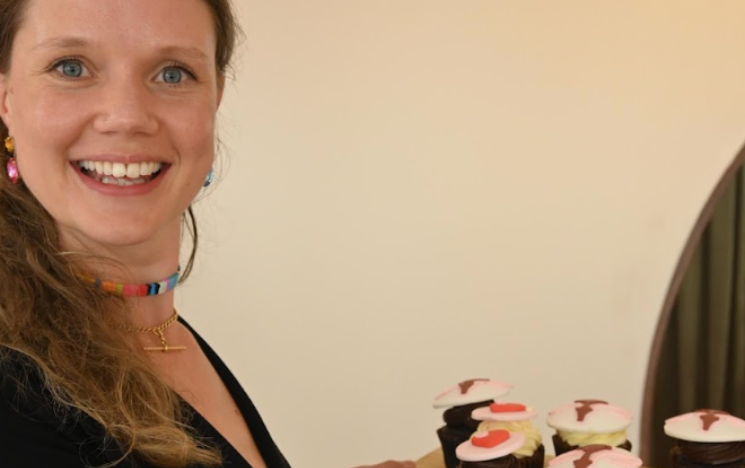 Poppy Hardy holding up cupcakes decorated with the female reproductive system.