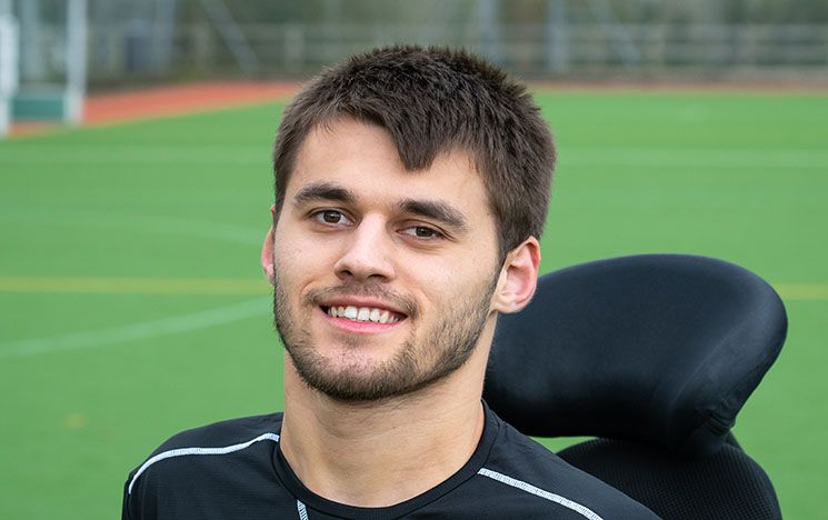 Louis Saunders, Sports Scholar smiling at the camera with a sports pitch behind him