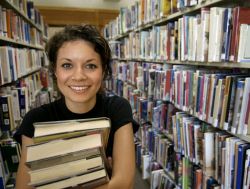student in library with arms full of books