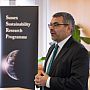 Zoomed in photo of keynote speaker and chair of this event, Prof Robin Banerjee, University of Sussex Pro VC for Civic and Global Engagement, present on "Global Engagement at Sussex". The SSRP Banner with a globe and the words "Sussex Sustainability Research Programme is pictured in the background