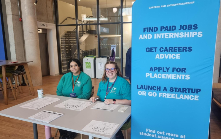 Careers team sitting behind a table, next to a banner promoting the summer fair