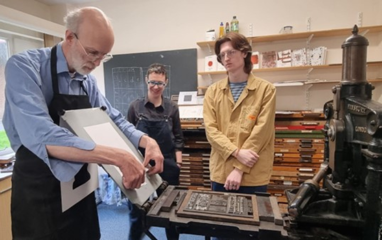 Students watching a demonstration of an old fashioned letterpress