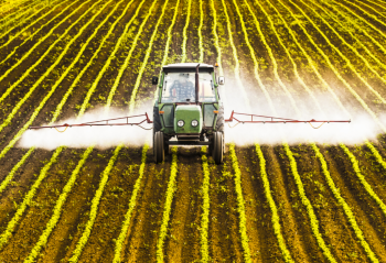 A tractor spraying a field of crops