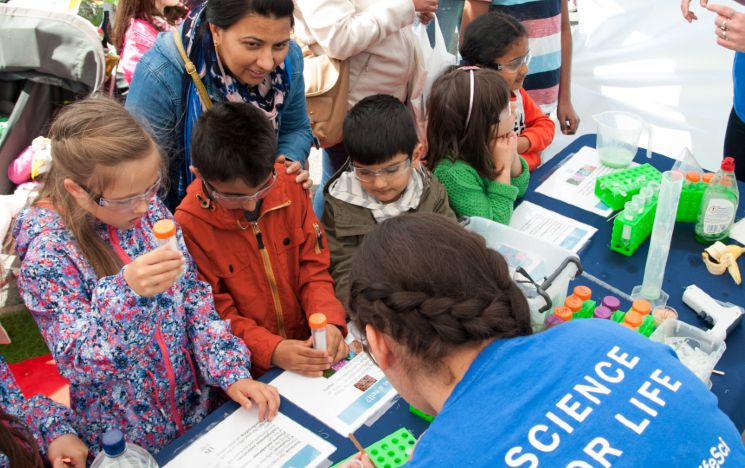 Scientists conducting a DNA experiment at a science fair with children