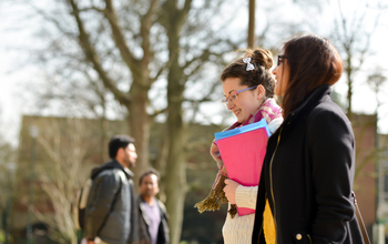 Students walking through campus with the sun shining down