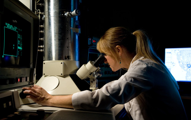 Biochemist looking through a microscope at the University of Sussex