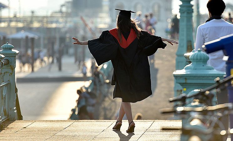 A student wanders on to the seafront in the sunshine after graduating