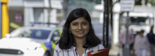 A student on placement poses in front of camera outside holding a folder